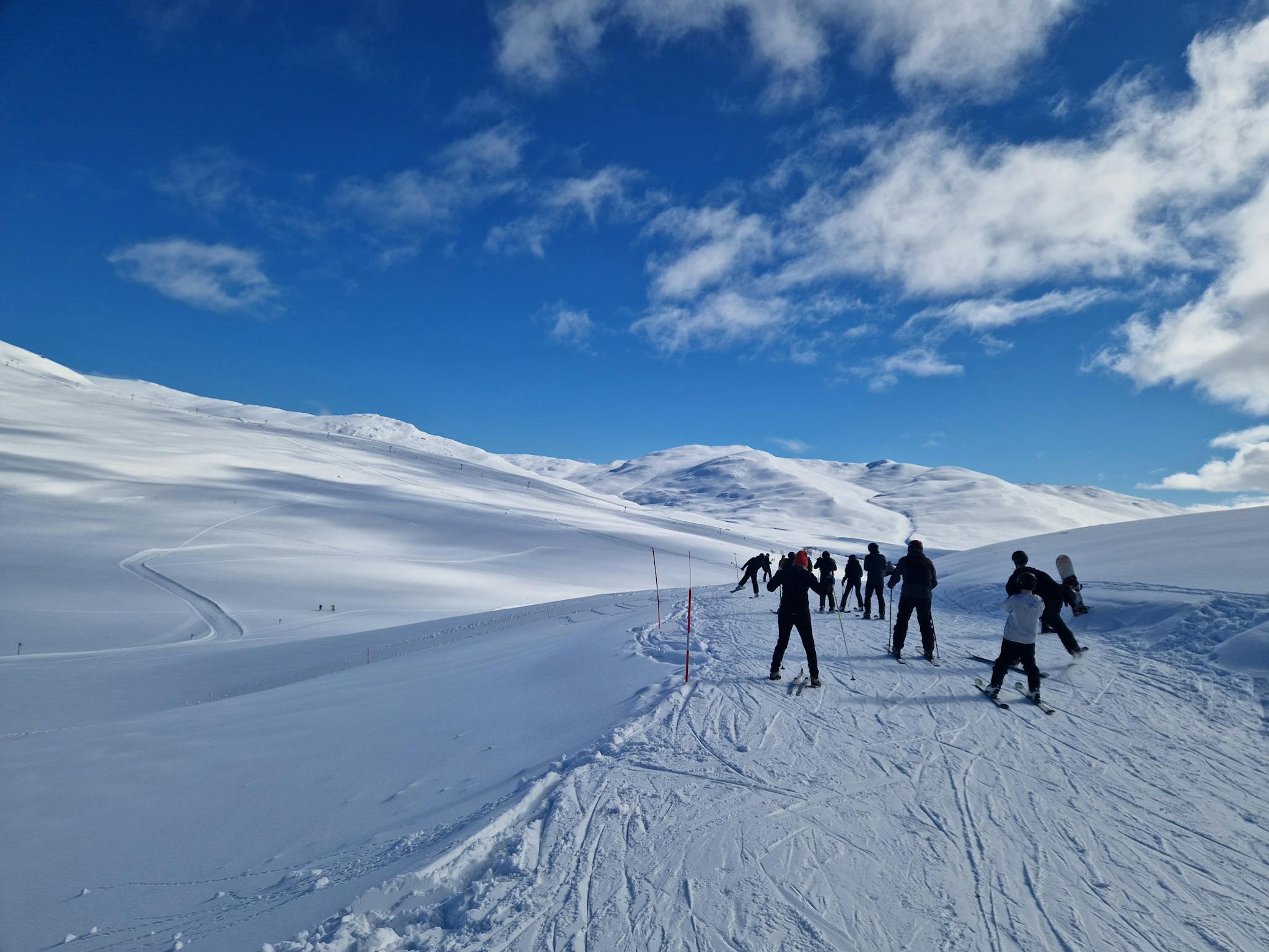 Group of skiers navigating snowy slopes in Hemavan, Sweden under clear blue skies.