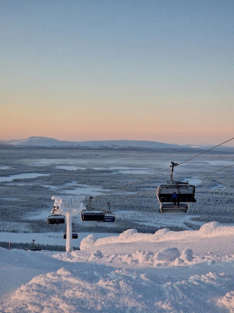 Scenic winter landscape featuring cable cars over a snow-covered mountain at sunrise.