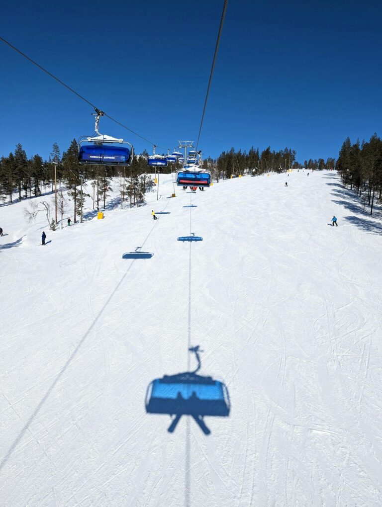 Snow-covered ski slope with ski lift on a clear winter day in Lapland, Finland.