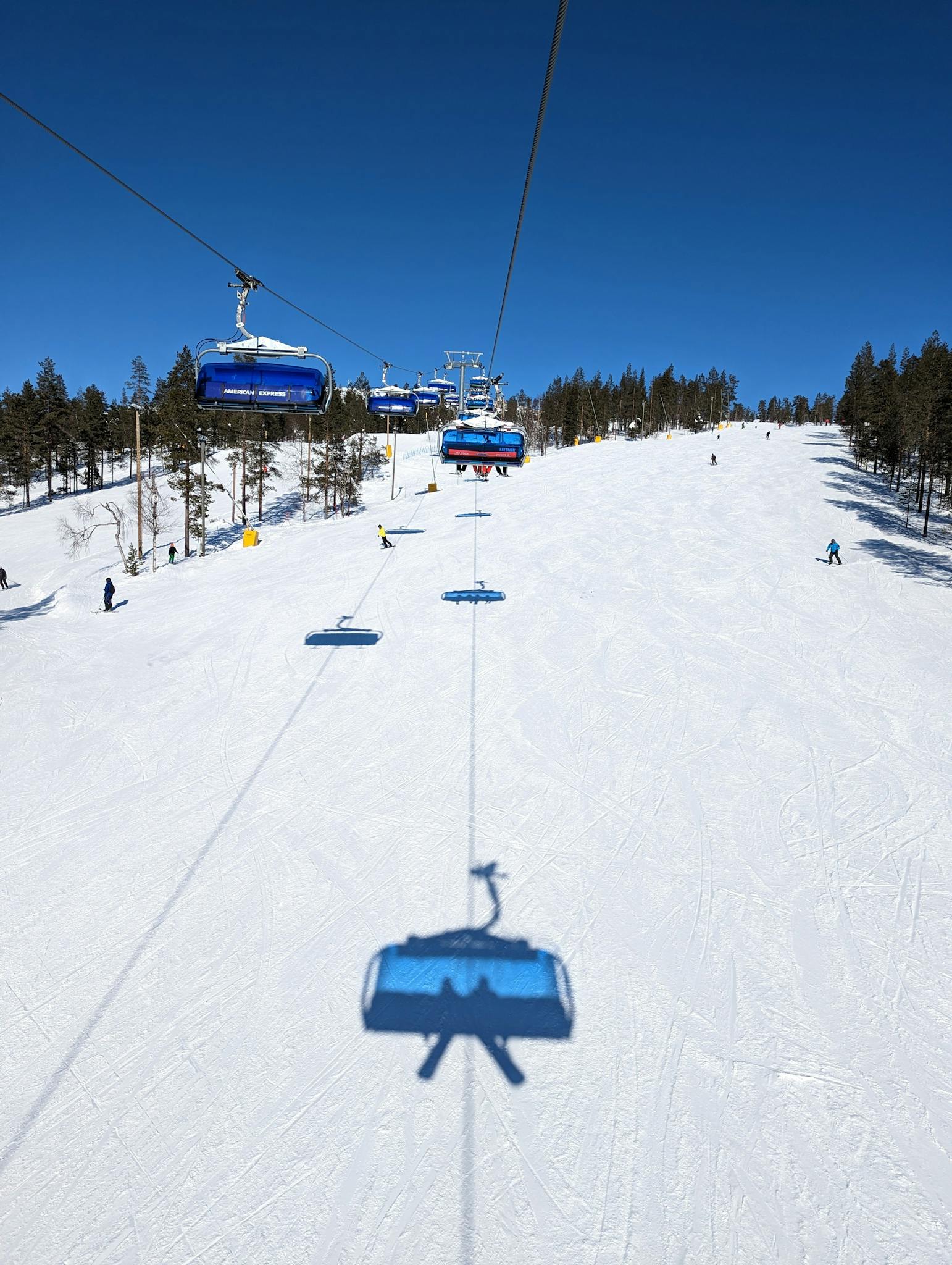 Snow-covered ski slope with ski lift on a clear winter day in Lapland, Finland.