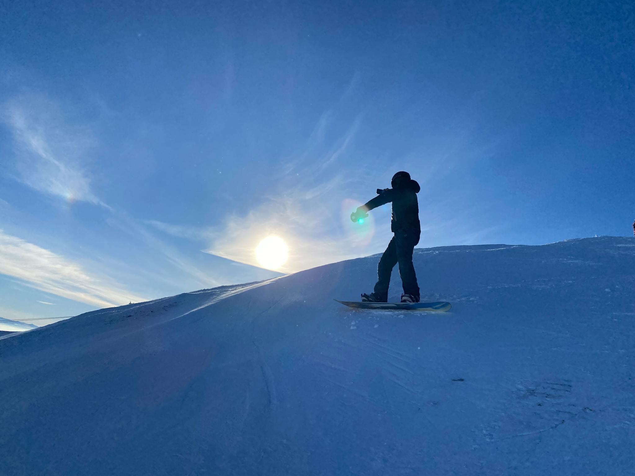 Snowboarder performing a jump on a snowy slope in Besse-et-Saint-Anastaise, France.